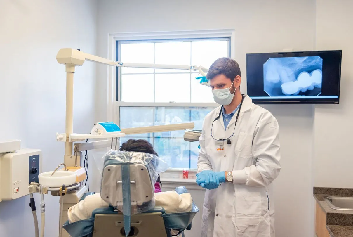 Dr. Kroner treating a patient in the chair, with an x-ray on the screen behind him